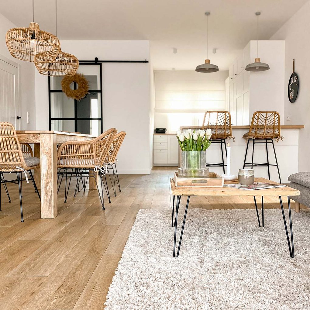 pokój dzienny z białymi ścianami i meblami z naturalnego drewna, rattanu i wikliniy