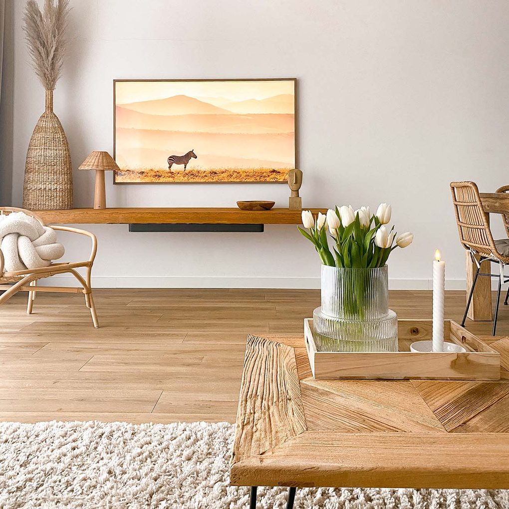 białe ściany, drewniane panele, drewniany stolik kawowy oraz dekoracje z plecionej trawy morskiej w salonie