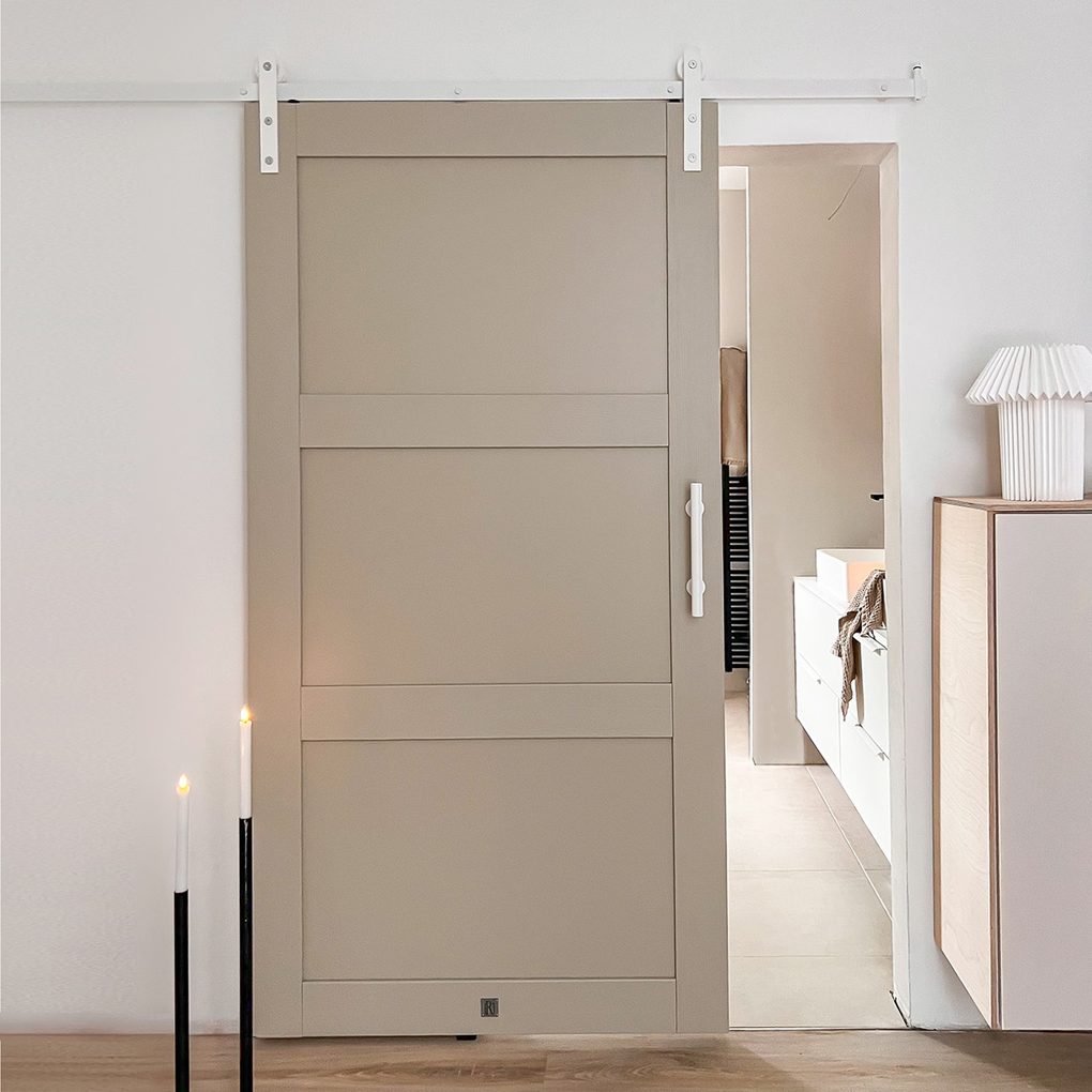 szaro-beżowe drzwi na białym systemie przesuwnym w wejściu do łazienki