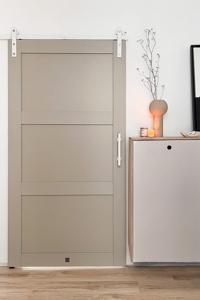 szaro-beżowe drzwi przesuwne z białym systemem i białą klamką