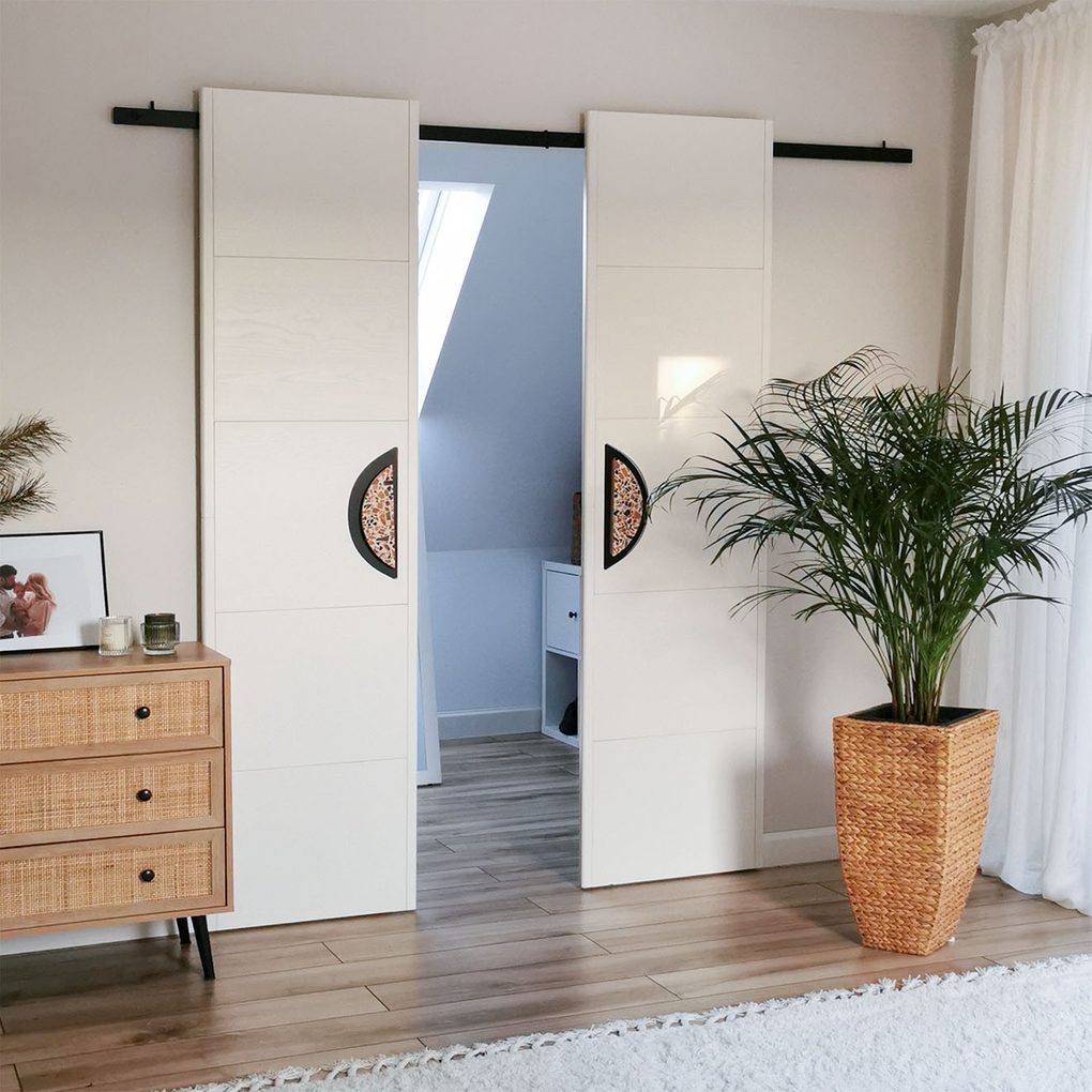 minimalistyczne, podwójne drzwi przesuwne z dużymi klamkami do małej garderoby w sypialni