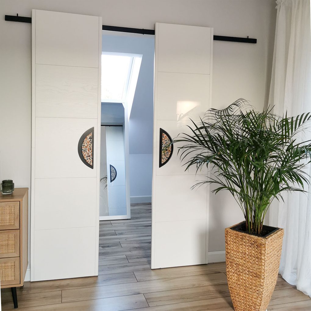 minimalistyczne, podwójne drzwi przesuwne z dużymi klamkami zamykające małą garderobę
