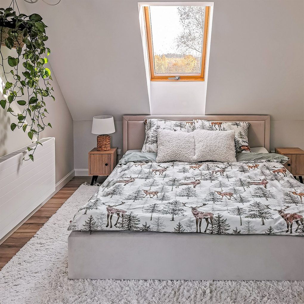 pościel z motywami leśnymi na tapicerowanym łóżku z zagłówkiem znajdującym się pod oknem dachowym